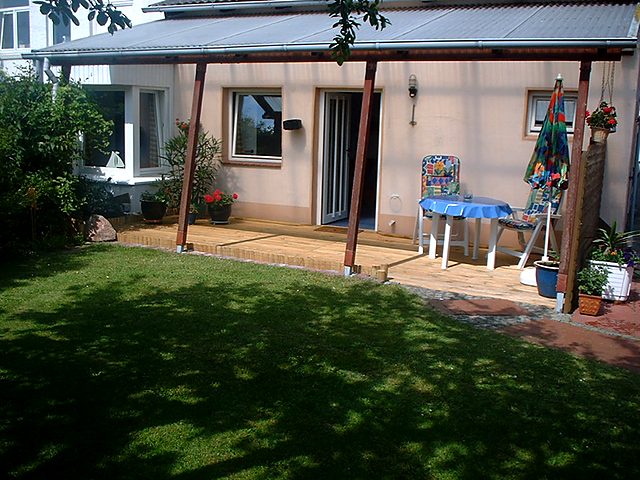 Ferienhaus: überdachte Holzterrasse und Garten