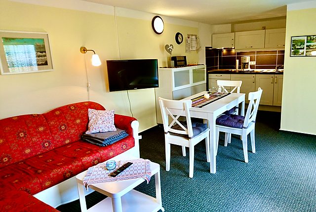 Ferienhaus: Wohnzimmer mit Sofa, Essplatz und Küchenzeile